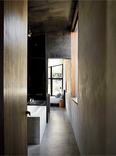 Richly Furnished Home Frames Striking Landscape Views - Photo 3 of 10 - Dulux Ferrodor 810 industrial paint in Mid Grey, dark formply timber ceiling cladding, and concrete floors give the interiors a brooding intensity.