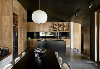 Richly Furnished Home Frames Striking Landscape Views - Photo 10 of 10 - The kitchen island is made from oxidized steel with a honed black marble benchtop. Cabinetry in blackbutt, an Australian hardwood known for its fire resistance, contrasts with the dark interiors.
