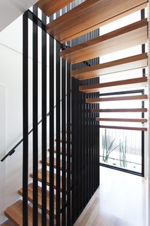 A Modular Beach Home in Australia Allows One Family to Keep an Eye on the Surf - Photo 6 of 8 - A striking stair defines the entry to the house; it features minimalist floating timber stair treads wrapped around a woven steel mesh blade wall.