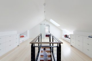 A Musty Attic is Transformed Into a Luminous Loft - Photo 2 of 7 - Smith designed the custom cabinets, which were fashioned from medium-density fiberboard with a white lacquer finish. There are three drawer heights. "The faces are consistent but some, when you open them up, are triple-height," Smith says. "So that helps with things that are really large, like sleeping bags or camping stuff or whatever. They're three feet deep, so it goes into the knee wall, which is really handy. So you get lots and lots of storage."