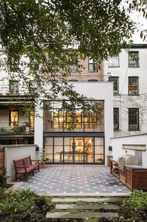 A Neglected Brooklyn Townhouse Becomes a Home That’s Primed for Entertaining - Photo 8 of 8 - Indoor and outdoor entertaining is made simple by the dining room’s sliding glass doors, but the two spaces also share a literal common ground. Lapicida’s tumbled black limestone with white Carrara marble inserts sprawl from the kitchen, past the dining room, and onto the patio.