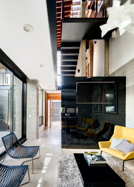 Old and new architectural elements were unified with a vertical stair cube, a central design feature. The living room of the new building sits at the base of the staircase. The furniture choices throughout the home were a product of their native space; classic pieces were used in the original building, while contemporary items were favored in the new wing. Living room furnishings include two Niels Bendtsen yellow park lounge chairs, opposite two Marcelo Ligieri black leather York Lounge Chairs. A wine cellar is cleverly tucked under the staircase. Photo 2 of Hybrid Home modern home