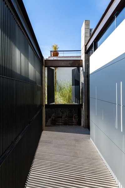 New balconies were constructed to complement the scale of the adjacent openings. The second story balcony was conceptualized as an extension of the room to the street. It can be closed when privacy is required, but opened to the street or terrace for interaction with the natural surroundings. The metallic blinds create dynamic shadow patterns as the light changes throughout the day. Photo 6 of Hybrid Home modern home