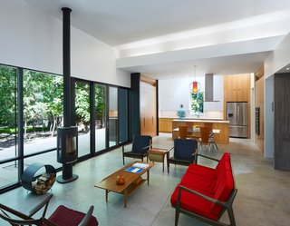 This Light-Filled, Metallic Home Embraces Its Wooded Site - Photo 6 of 8 - Floor-to-ceiling windows, complemented by a wood-burning stove from Jøtul, bring the outdoors in. "Movement throughout the house—down the hall, through a doorway, or across a room—is always toward a view of the outdoors, creating a connection between the inside and outside," Hart says.