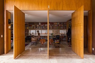 This Cor-Ten House in Brazil Would Not Be Complete Without its Giant Home Library - Photo 4 of 7 - The library’s entrance features massive panel doors made of tropical freijó wood. Inside, leather armchairs by Jorge Zalszupin accent the space.