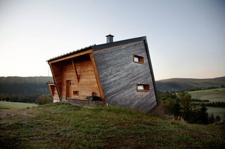 Sebastian Heise’s wooden structure, seemingly atilt, overlooks a green valley in Oberwiesenthal, Germany. The two horizontal windows on the side and the front porch give the home its own unique sense of balance.