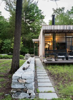 A Couple Takes an Unassuming Plot of Land and Calls it Home - Photo 3 of 11 - Outside, Sultan added a stone wall to anchor and extend the structure into the landscape.