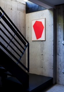 A Couple Takes an Unassuming Plot of Land and Calls it Home - Photo 6 of 11 - A red print by Cris Gianakos accents a well-lit stairwell leading to a laundry area, library, and rec room on the full basement floor.