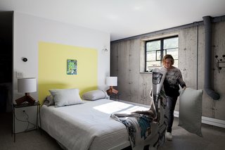 A Couple Takes an Unassuming Plot of Land and Calls it Home - Photo 8 of 11 - Furnished with Rakks shelving, a Blu Dot table, and a sofa bed from ABC Carpet & Home, the floor also includes a spacious guest bedroom. A bright-yellow color accent, painted onto the wall in Benjamin Moore’s Sunburst, acts as a subtle, minimalist headboard.