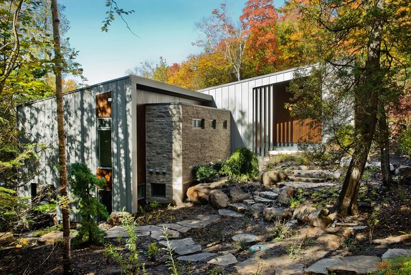 “The site was beautiful as it is,” architect Eric Tremblay said, and he wanted to build a home that had the least impact on the terrain as possible. The lake can be seen on either side of the house, and natural materials—like the Eramosa limestone coating on the exterior—were a priority during construction. Photo of Chalet Lac Gate modern home