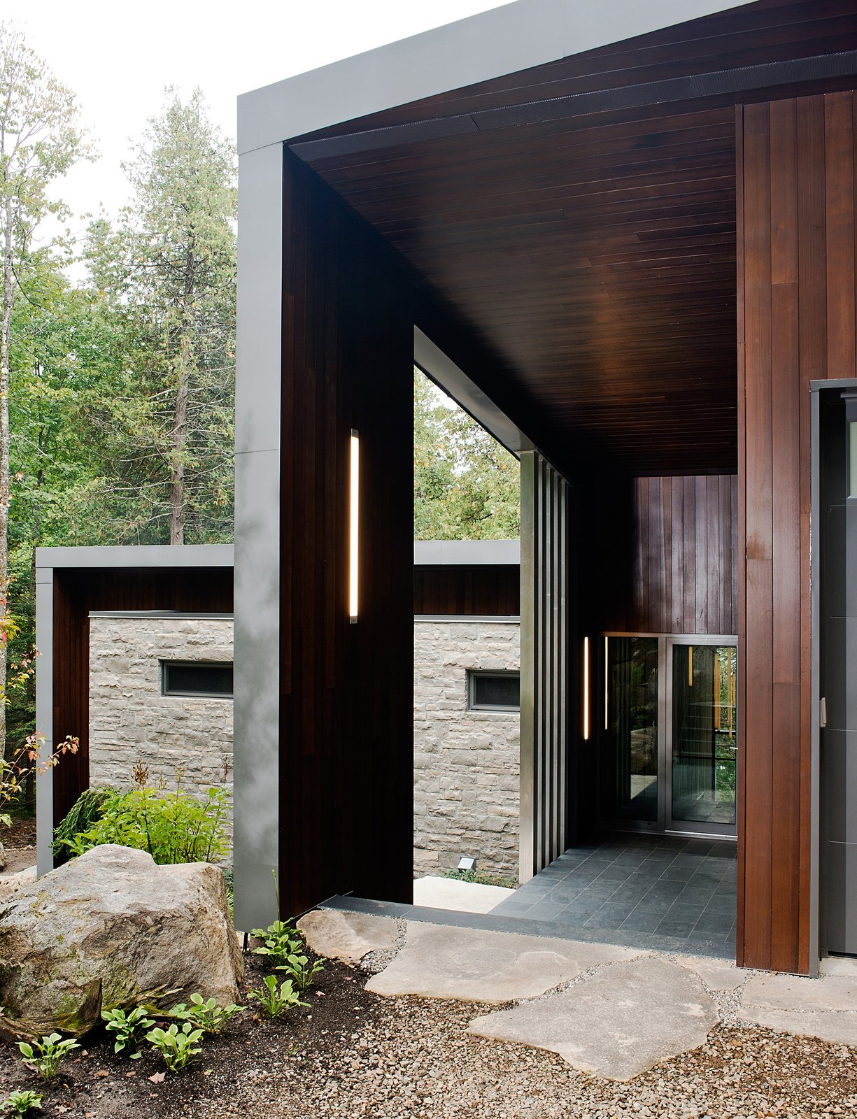 Tremblay chose materials that would reflect the natural setting, like the Polylam-C cedar siding from Prorez, used at the home’s entrance. The exterior floor finish is Montauk grey slate.
