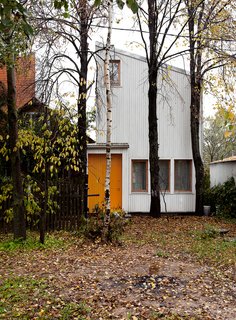 A Compact Home in Moscow Built on the Lowest Possible Budget - Photo 1 of 9 - "Our goal was to construct a house with the lowest possible budget, while ensuring comfort and efficiency for the residents inside," says Sergey Kolchin, founder of Le Atelier. The architects accented the home’s front door by painting it yellow, harmonizing the structure with the surrounding forest.