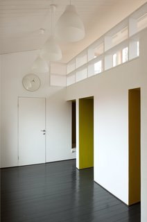 A Compact Home in Moscow Built on the Lowest Possible Budget - Photo 7 of 9 - Inspired by "polati," a sleeping loft that featured prominently in traditional Russian homes, Le Atelier created a series of tiny bedrooms that connect to a playroom with a study upstairs. A clock and lights from IKEA blend into the room’s simple color palette.
