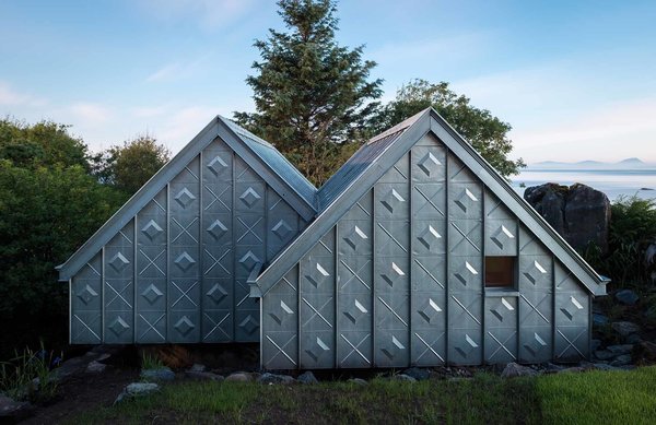 The studio is located in the natural context of the Scottish coast, with the island of Jura in the distance. A significant design challenge, according to Blake, was “building something quite refined in an extreme and remote environment.” To overcome this logistical obstacle, much of the material was prefabricated offsite and transported to the building location. At the facade, elemental zinc is elevated from raw material to art piece by the unique cladding pattern. The custom embossed standing seam zinc system was designed in collaboration with VM Zinc, and fitted by HLMetals. Photo of Midden Studio modern home