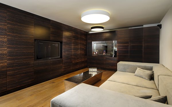 Downstairs in the basement, an entertainment room is inspired by the idea of an English pub. Dark, rich wood tones are favored in this popular meeting place for friends. The space was designed to be soundproof in order to maintain privacy from the two older children's bedrooms, also on the basement level. A wine bar, flat screen TV, and stainless steel table complete the space. Photo 7 of Rishon Le Zion 3 modern home