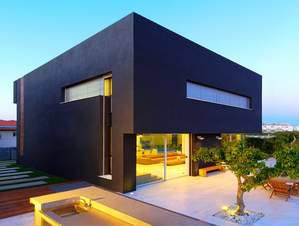 The voluminous black plaster cube appears to float over the open first-floor at the rear elevation. On the roof, solar panels generate about 80 percent of the home’s electrical and heating needs. The landscaped backyard was designed to resemble an orchard, and includes several defined areas for socializing and entertaining. Photo 8 of Rishon Le Zion 3 modern home