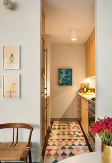 The galley kitchen features space-saving appliances like an 18-inch-wide Miele dishwasher and 24-inch-wide Liebherr refrigerator; LED light strips are tucked beneath the cabinets.
