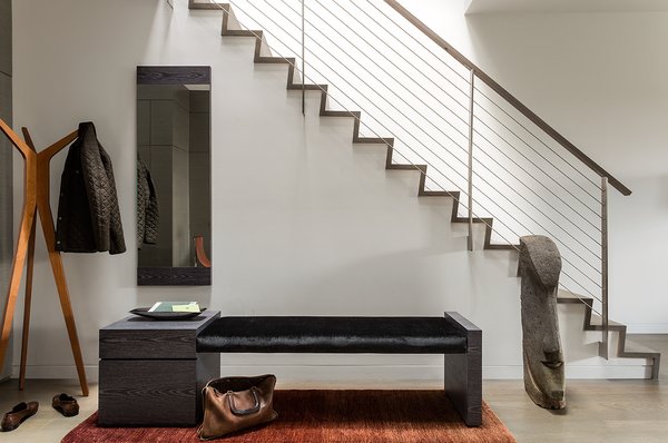 “The entire house is unified with oak flooring with a custom warm gray stain. This material is repeated on the stair and atrium handrails,” Walker said. The entryway’s bench has a custom Tabu Caleidolegno veneered wood base. The upholstered bench seat, which uses black Kravet fabric, was designed by Ruhl Walker Architects and made by Herrick & White. Photo 2 of Back Bay modern home