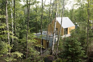 The facade consists of exposed concrete, Galvalume roofing, and cedar or torrefied wood coating. The homes are carefully positioned to keep other structures out of sight.
