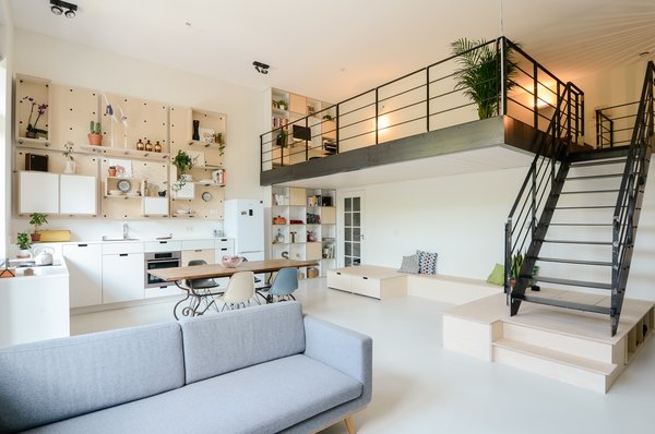 The old classroom space is now an open-concept living and family room. With a family of five and limited interior space, creative storage solutions were essential to the functionality of the home. Simple birch plywood built-in storage under the stairs provides a place to stash kids’ toys, as well as a platform for playing and sitting. Concrete floors flow through the entire home. Photo of The Schoolhouse modern home