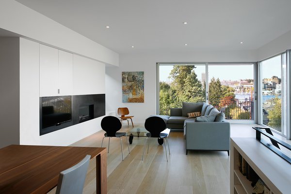 “The primary architectural strategy was to connect the exterior entry, primary interior living spaces, and exterior patio as a continuous spatial experience,” Hutchison says. Fleetwood Windows & Doors supplied the sliding pane to the outdoors. A crescent sectional by Camerich sits across from a custom steel-plate fireplace designed by Hutchison. Photo 4 of Portage Bay Bungalow modern home