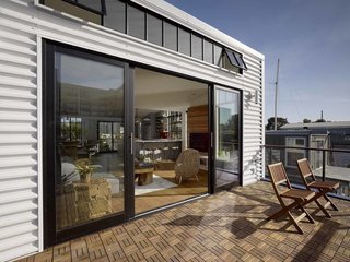 A pair of Amazonia Terra teak chairs sit atop the first-floor deck, covered in Runnen teak outdoor floor decking from IKEA.