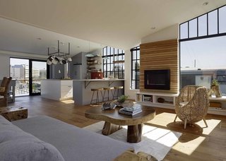 The living room floor is made of Australian cypress with a tung oil finish. A Solas wall-mounted fireplace by Hearth Innovators and a curious chair, by Putra Salahin in Bali, complement the sun-drenched space.