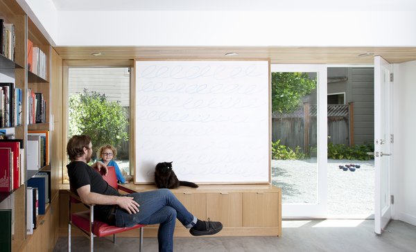 Averse to the idea of a television being the centerpiece of a space, the owners instead opted for a clever alternative in the library/media room. Continuing the theme of movable and multi-functional design elements, a rolling chalkboard panel was designed to conceal the TV when not in use. Throughout the home, the family’s furniture is an eclectic mix of purchased, custom built, inherited, and self-made pieces. The room is accented with a reclaimed red office chair with custom white oak armrests made by Scholz. Photo 3 of KS Mission modern home