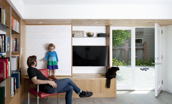 The sliding wall panel is seen in its open position. In addition to several design elements serving multiple functions, great care was taken to develop a compelling design within the constraints of existing conditions. The remodel was confined to the existing building envelope, leaving the original footprint unchanged, but adding about 650 square feet of habitable space in the process. “The plans,” explains Paré-Mayer, “respected existing structural conditions where possible to save on cost.” The finished concrete floor is, in fact, the structural slab, an efficient choice from a cost and materials perspective. The existing footings, which were wider than the framed interior walls, were kept intact in their original condition and location. The team was able to cleverly design around them by building usable closed storage to conceal the protruding foundation, as seen at the base of the media built-in. Photo 4 of KS Mission modern home