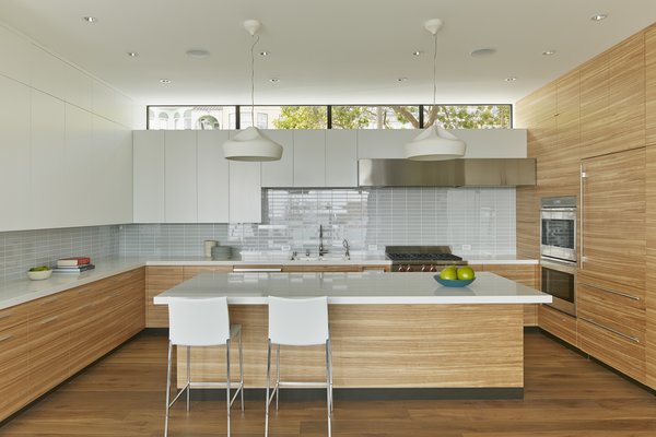 The architects wanted to create as much of a buffer as possible against the urban traffic outside the kitchen. A clerestory window manages to maintain a visual connection with the neighborhood while blocking its noise. The kitchen features Pleat Box pendant lights from Marset and Lio Stools by Roberto Barbieri for Zanotta. Photo 2 of Noe Residence modern home