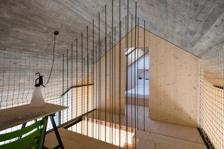 Steel rods surround the staircase. A MayDay lamp by Konstanting Grcic for Flos is affixed to the rope wall.