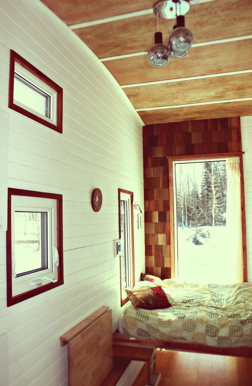 A custom Murphy bed occupies the rear end of the trailer, next to a wall of cedar shingles. The wall at left, which Herbert painted white, is tongue-and-groove pine.