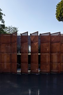 This Cor-Ten House in Brazil Would Not Be Complete Without its Giant Home Library - Photo 2 of 7 - The Cor-Ten panels make up the library’s lateral facade and act as a light filter, preventing direct sunlight from penetrating in. The dynamic panels dramatically transform the appearance of the front facade, whether open or closed.