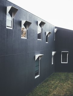 Modern House Captures Panoramic Views in Australia - Photo 3 of 5 - The cement exterior walls were painted in a dark color to blend in with the forest. Aluminum window frames add some texture to the facade.
