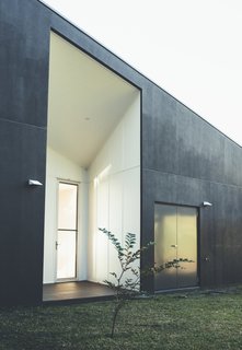 The house uses solar panels and water tanks to function off the grid. Its waste water is recycled and used for irrigation. This door is framed with a massive, geometric opening that's both dramatic and minimal at the same time.
