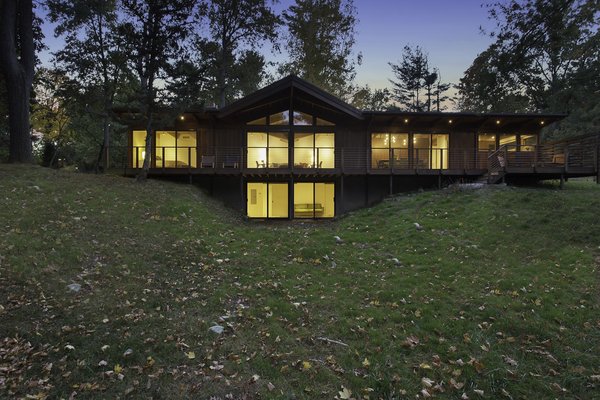 “The use of the structural insulated panels for the roof allowed us to keep the exposed post-and-beam look, which is a midcentury trademark, while making the house energy-efficient,” Schultz said. Douglas firm beams and soffits support a SIPS roof, which shades Andersen Windows & Doors. The deck, made of red meranti, overlooks a nearby pond. Photo of City Skyline modern home