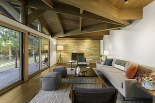 25 Homes With Exposed Beams: Rustic to Modern - Photo 11 of 25 - Stained white oak spreads across the living room under Douglas fir beams. At the far end of the room, a Jonathan Adler lamp stands next to an original limestone fireplace that was restored.