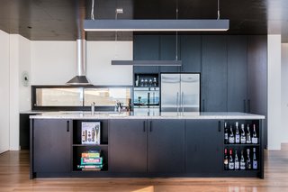 An Australian Beach Home with Stunning Ocean Views - Photo 5 of 8 - A granite island countertop and black American oak cabinetry are a winning combination for the utilitarian kitchen. The sleek kitchen pendant lights are Matric-P4's from Lightnet.