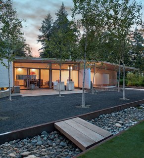 "They wanted the new cabin to make a ‘L’ shape with the older cabin, but I convinced them to mimic the old cabin on the opposite side," architect D’Arcy Jones says. "So the new site has two buildings across from each other, like an equal sign." Birch trees grow between the cabins in a shared courtyard.