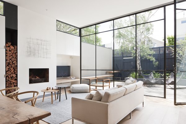 The designers explain, “These steel windows played an integral part in making the interior feel larger and more open by blurring the boundaries between the interior and exterior.” A grey Halcyon Lake area rug, an oak chair from MAP, and Hans Wenger Wishbone chairs make for a simple, neutral palette. The painting over the fireplace is by Kate Hendry. Photo 3 of Seclusion modern home