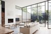 Modern home with living room, chair, sofa, coffee tables, light hardwood floor, and wood burning fireplace. The designers explain, “These steel windows played an integral part in making the interior feel larger and more open by blurring the boundaries between the interior and exterior.” A grey Halcyon Lake area rug, an oak chair from MAP, and Hans Wenger Wishbone chairs make for a simple, neutral palette. The painting over the fireplace is by Kate Hendry. Photo 3 of Seclusion