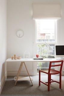 The study has a fun, playful atmosphere thanks to a red Square Dining Chair from MAP, a Tempo wall clock by Naoto Fukasawa for Magis, and house sculpture from David Band.