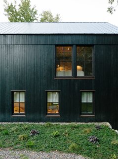The main house is constructed from structural insulated panels from Vermont Timber Frames and clad in charred cedar. The roof panels are by Agway Metals.