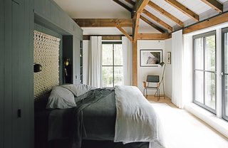 The bedding is intentionally simple, without layers of unnecessary pillows, and the "non-headboard headboard," as Santos describes it, is a loose macramé wall hanging by Sally England. The built-in storage wall that defines the space is painted Kendall Charcoal by Benjamin Moore in a matte finish—a shade used on millwork throughout the house. The Isaac brass sconces are from Schoolhouse Electric, and the floor lamp is from Crate & Barrel. The rocker was custom made by Onefortythree in Las Vegas.