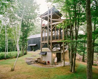 Connected to the main house by a narrow bridge, a three-story cedar tower with a sauna at its base recalls a tree house. The screened-in second level includes a table and chairs for enjoying an outdoor meal, while a swing on the tower’s top level provides a perch to take in the surrounding birch trees.