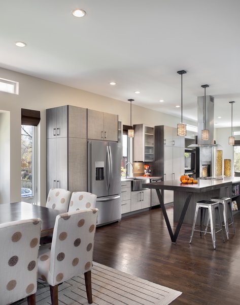 “Because the property is so narrow, we had to be strategic in laying out the plan,” Mitchell says. “Our goal was to create an open plan that spanned from exterior wall to exterior wall in order to make the home feel as large as possible.” Solid oak flooring fills the space and pendants from Kenroy Home illuminate the kitchen. Photo 3 of Highlands House modern home