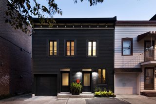 30 All-Black Exterior Modern Homes - Photo 27 of 30 - The owners’ goal was to transform the 19th-century building into a bold single-family residence. Historical architectural details were made modern with a striking black facade, while inside, a flexible living space that opens into an exterior garden enables a simplified lifestyle.