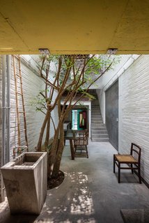 The common area, a long open alleyway on the ground floor, serves as a gathering place, dining room, and playground for the children. This is where family members interact, communicate, and build relationships, all while exposed to the changing seasons through the net ceiling, which is open to the sky.