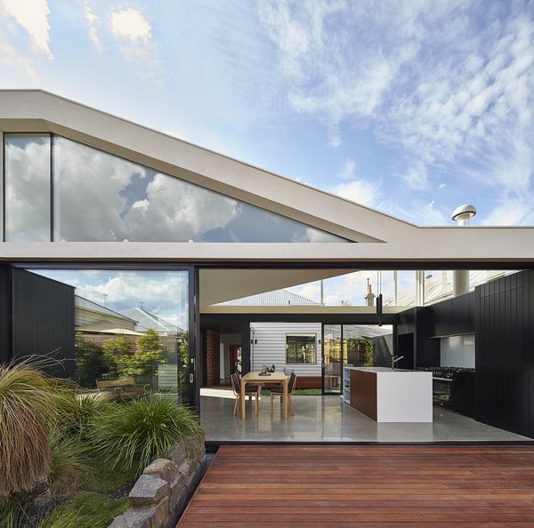 “From the beginning we knew we needed to remove the rear 80s extension and preserve the front Edwardian home,” architect Michael Ong says. “So, we were interested in how the two different architectural styles would work together.” The old Edwardian home can be seen in the center of the frame, through the dining room and kitchen of the addition. Merbau Decking extends into the garden, which became the focal point of the home. Photo of Breeze modern home