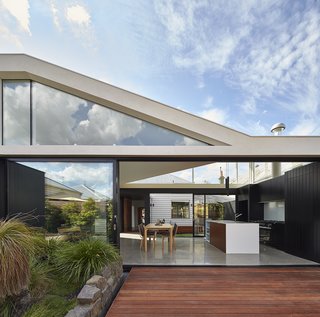 "From the beginning we knew we needed to remove the rear 80s extension and preserve the front Edwardian home," architect Michael Ong says. "So, we were interested in how the two different architectural styles would work together." The old Edwardian home can be seen in the center of the frame, through the dining room and kitchen of the addition. Merbau Decking extends into the garden, which became the focal point of the home.